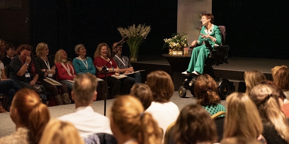 Joy op podium met voor en links en rechts van haar publiek 