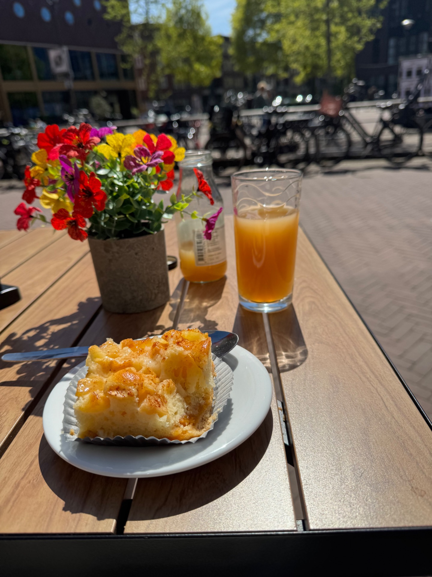 Op een tafeltje staan een glas sinaasappelsap en een stuk appeltaart